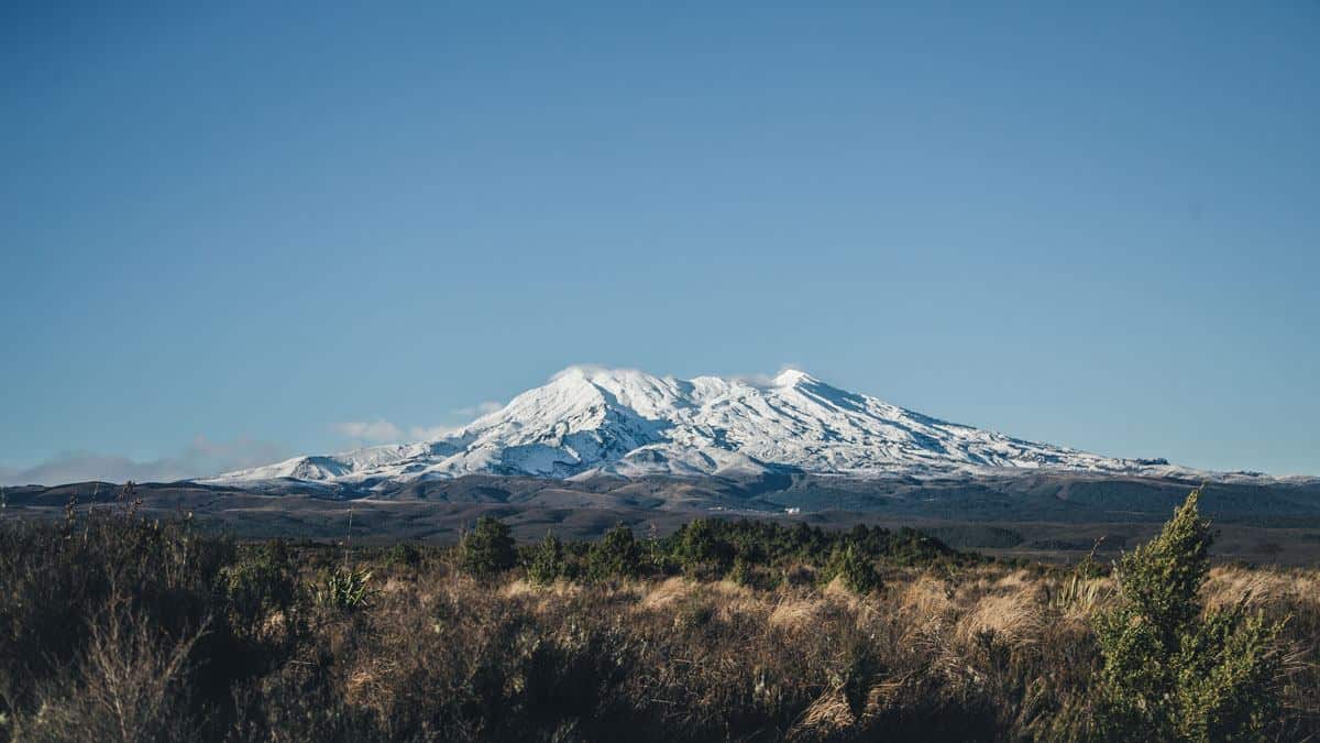 Ein einsames schneebedecktes Gebirgsmassiv steht in einer weiten Ebene des Tongariro Nationalpark