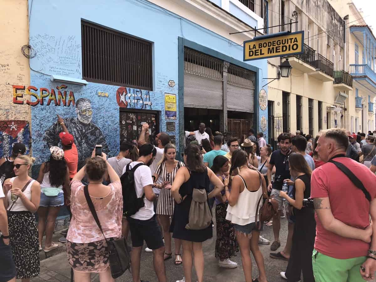 Touristen verewigen sich vor der Heminway Bar La Bodeguita an der Wand