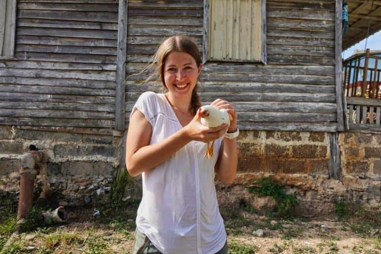 Eine Frau hat ein weißes Huhn in der Hand