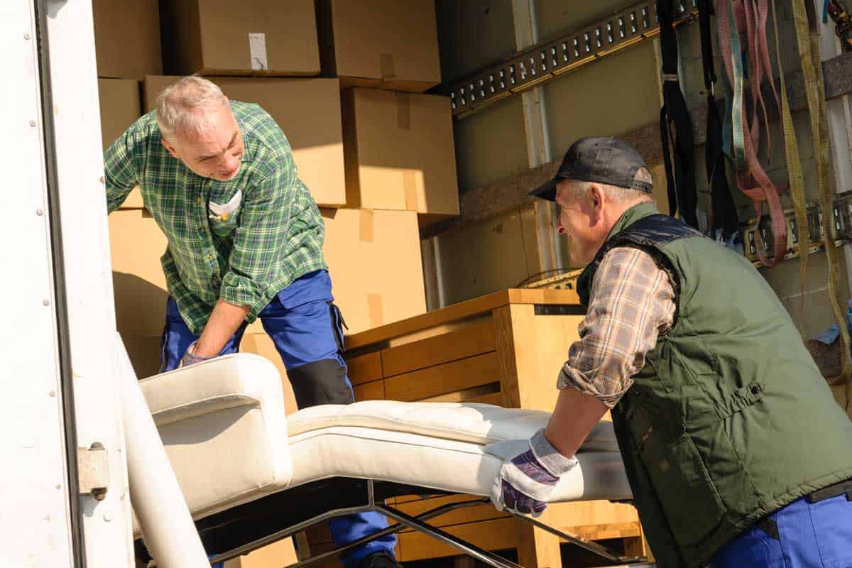 Möbelpacker helfen beim Umzug und tragen Möbel aus einem Haus