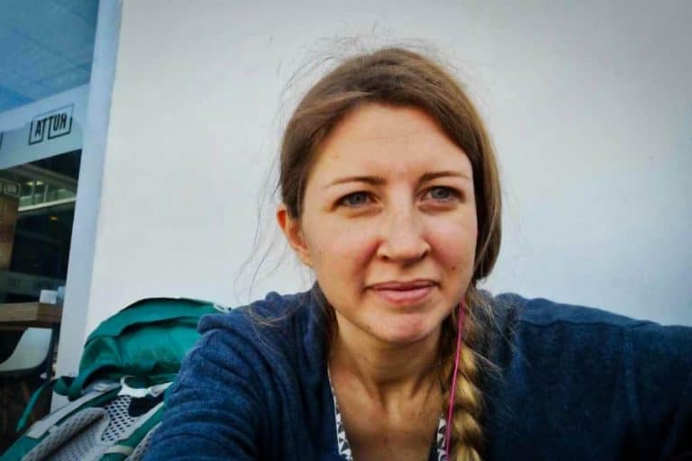 Backpackerin sitzt am Flughafen von Piura in Peru neben ihrem Backpack Rucksack