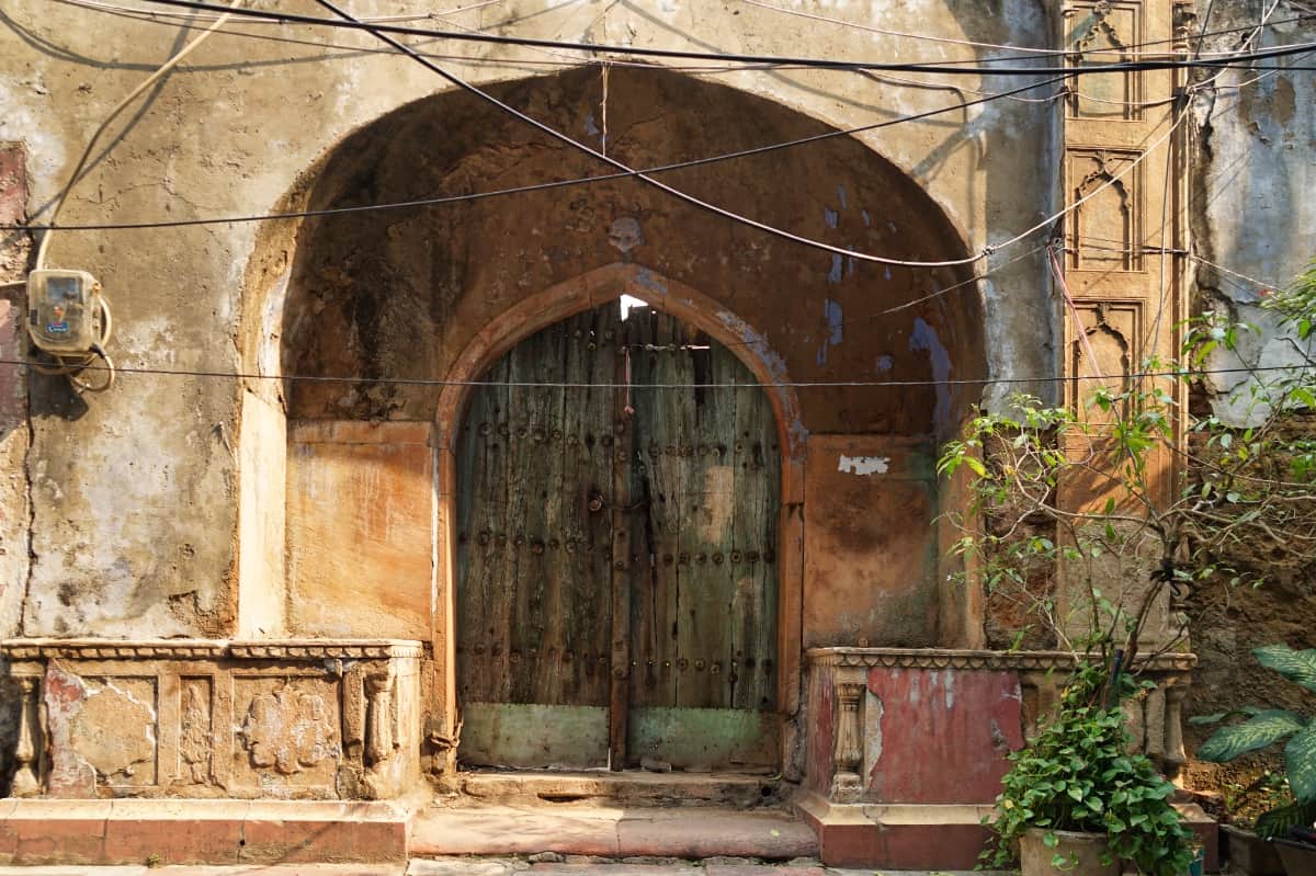 Ein historisches Gebäude aus Sandstein in einem Wohnviertel mit einer sehr schönen blau grünen Tür im traditionellen indischen Stil