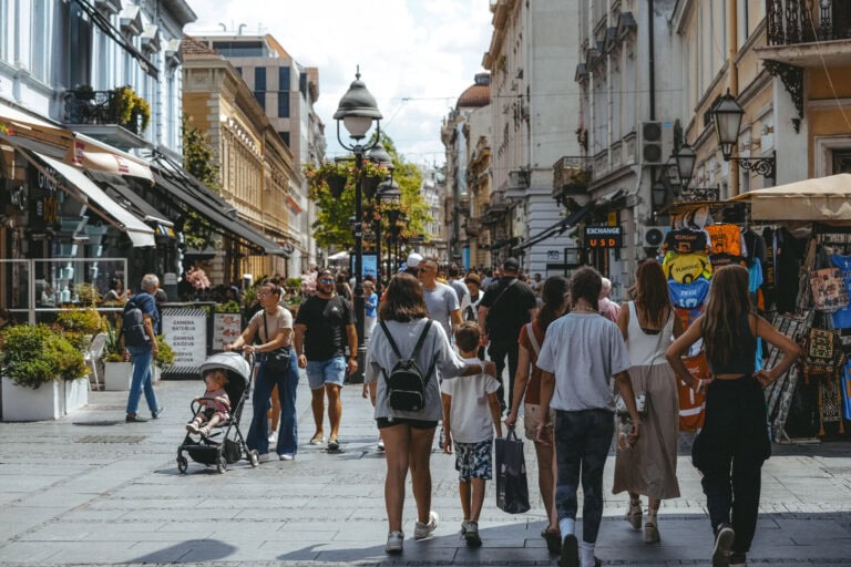 Belebte Fußgängerzone mit Menschen, die an einem sonnigen Tag spazieren gehen, einkaufen und Straßencafés besuchen, die eine lebendige und dennoch entspannte Atmosphäre mit viel Sicherheit bieten.