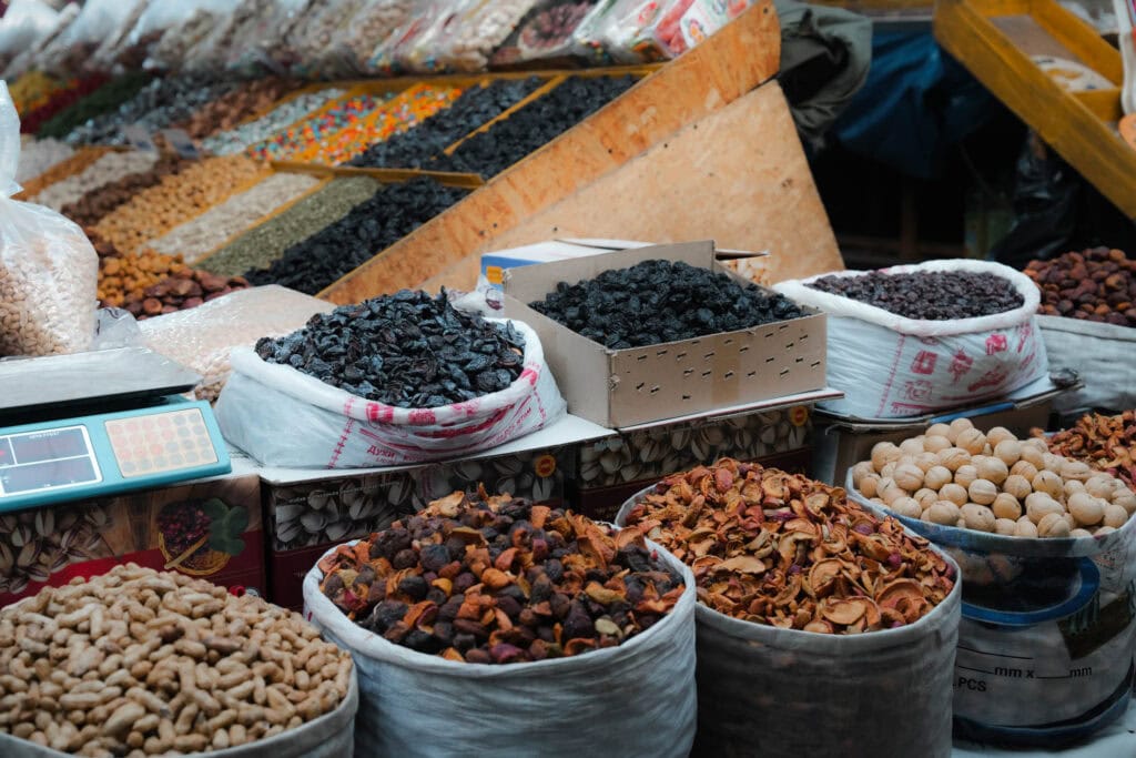 An einem Marktstand sind Tüten und Schachteln ausgestellt, die mit verschiedenen Trockenfrüchten, Nüssen und Gewürzen gefüllt sind.