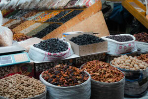 An einem Marktstand sind Tüten und Schachteln ausgestellt, die mit verschiedenen Trockenfrüchten, Nüssen und Gewürzen gefüllt sind.