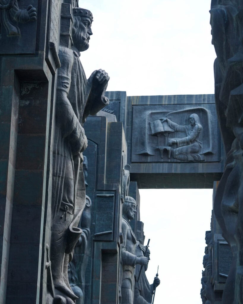 Große Steinstatuen und Reliefschnitzereien, darunter eine sitzende Figur, bilden eine monumentale Freiluftanlage.
