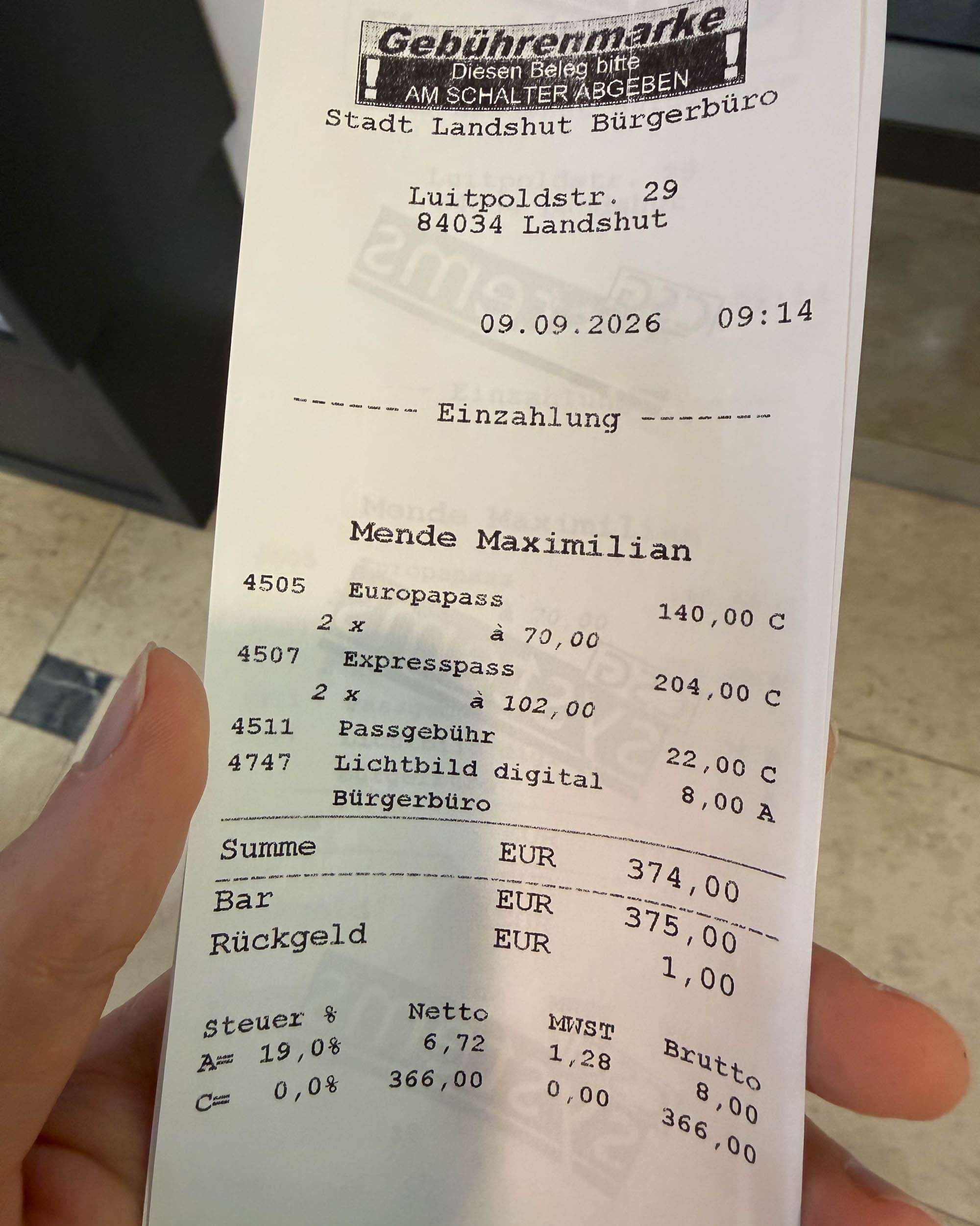 Eine Nahaufnahme einer deutschen Quittung über Passgebühren, die in einer Hand gehalten wird und auf den 9. September 2026 datiert ist.