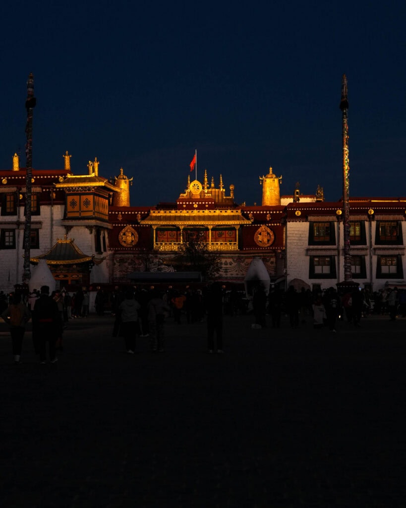 Nachts versammelt sich eine Menschenmenge vor dem beleuchteten Jokhang-Tempel.