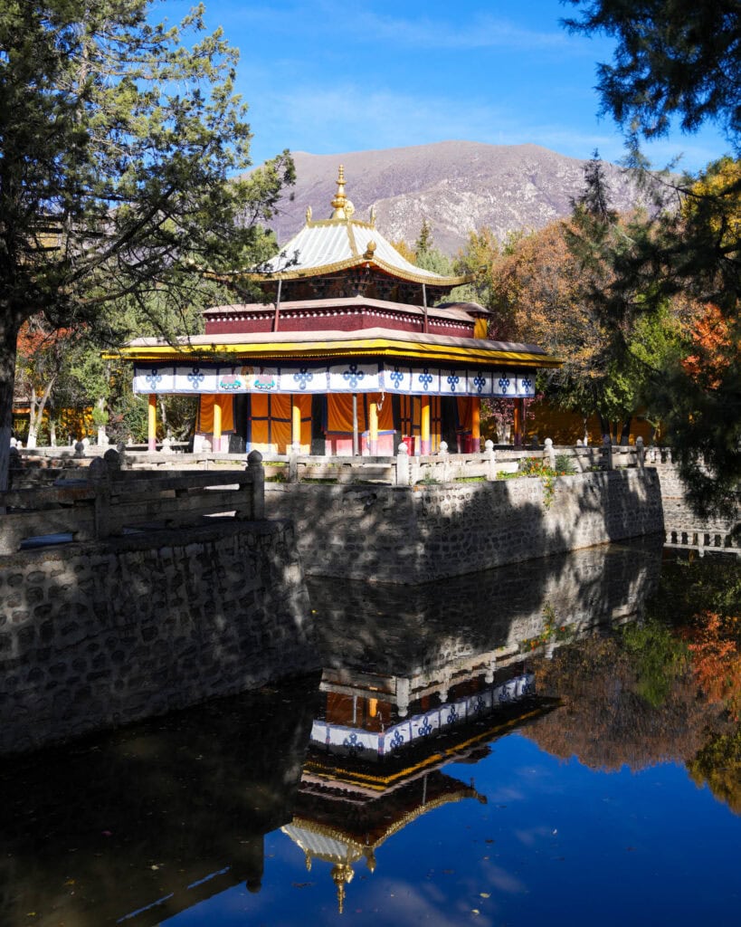 Ein buddhistischer Tempel mit einem stufenförmigen goldenen Dach, das sich in einem ruhigen Teich spiegelt.